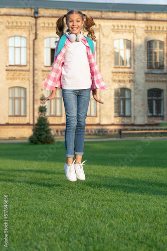 Happy energetic teenage girl jumping in school yard outdoors, Knowledge day