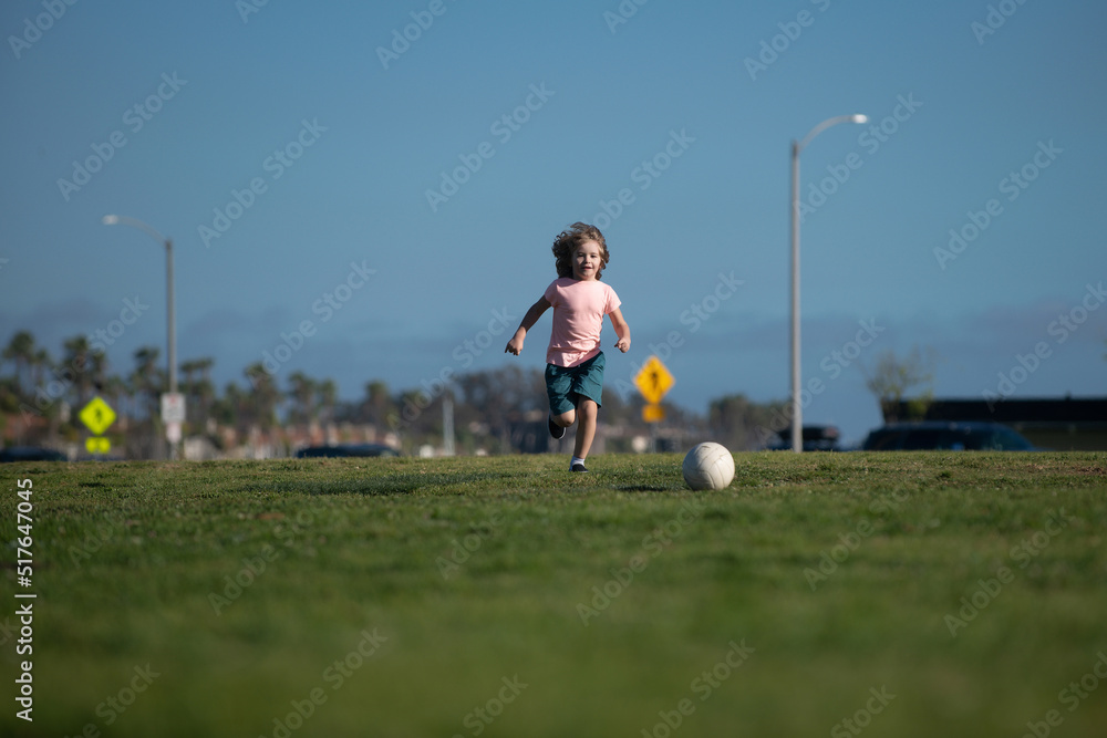 Boy football player kicking football on the sports field. Active kids. Child soccer. Kids play soccer game.