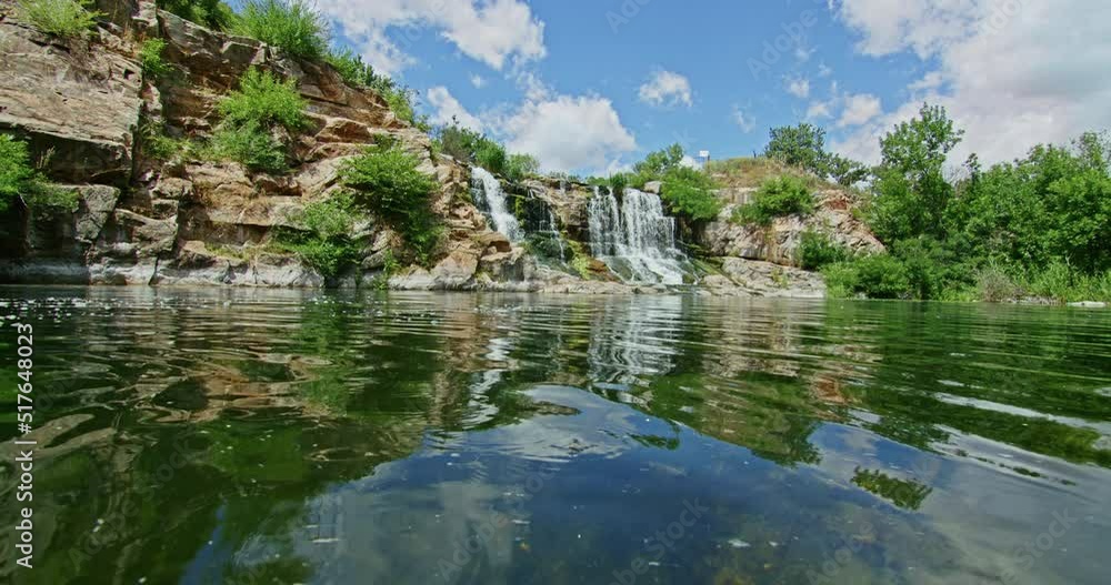 a beautiful mountain waterfall flows through the rocks, its water washes stones and trees a beautiful mountain waterfall flows through the rocks, its water washes stones and trees
