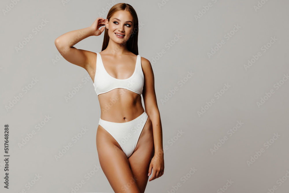 Young pretty woman with perfect slim body. Beautiful model wearing inner  wear, smiling and posing on grey background. Concept of beauty, body and  skin care, health, plastic surgery, cosmetics, ad Stock Photo