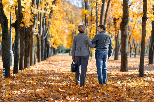 portrait of a romantic couple in an autumn city park, a man and a woman walking and posing against the background of yellow maple leaves, a bright sunny day