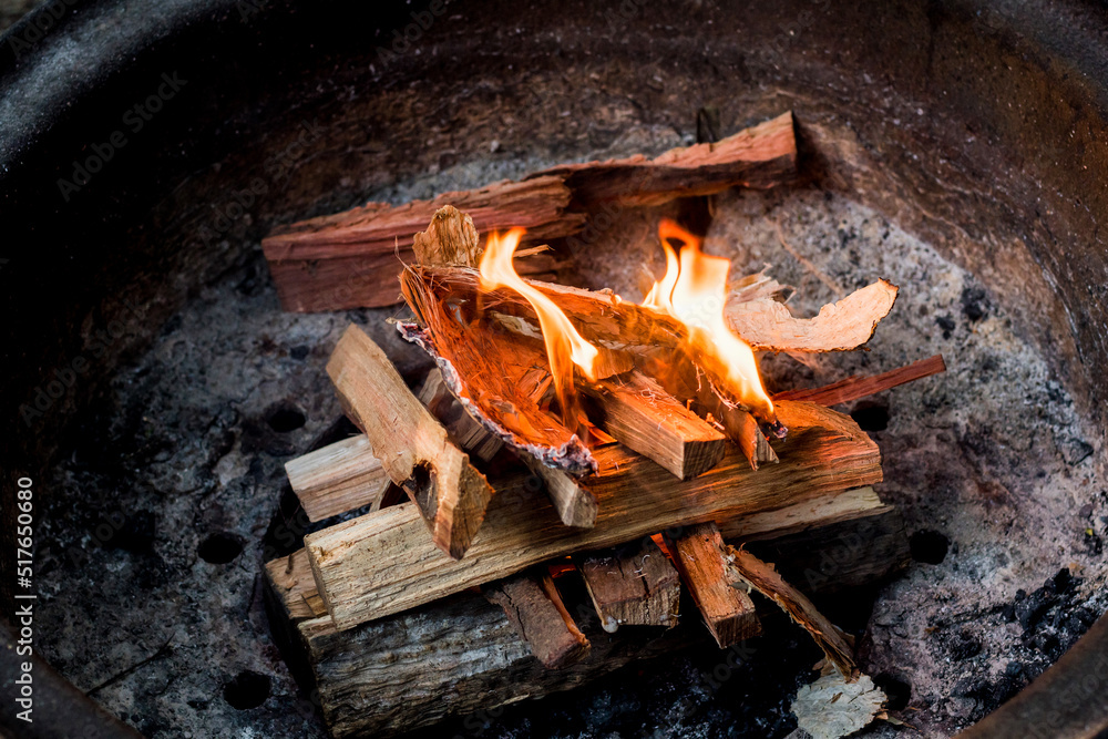 Starting a campfire in a firepit with kindling. Camping lifestyle. - obrazy, fototapety, plakaty 
