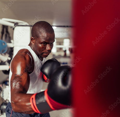 Strong muscular boxer working out with a punching bag