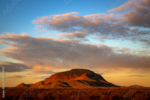 An image of beautiful sunset, clouds, sky, and red rock Mt Robinson in Karijini national park, Western Australia