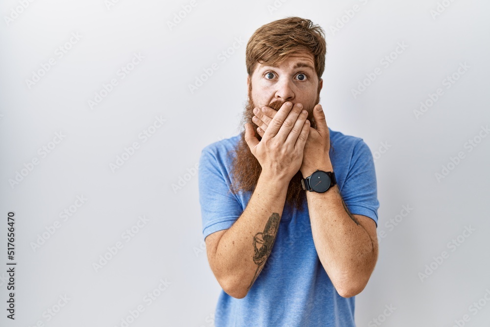 Caucasian man with long beard standing over isolated background shocked covering mouth with hands for mistake. secret concept. Caucasian man with long beard standing over isolated background shocked covering mouth with hands for mistake. secret concept.