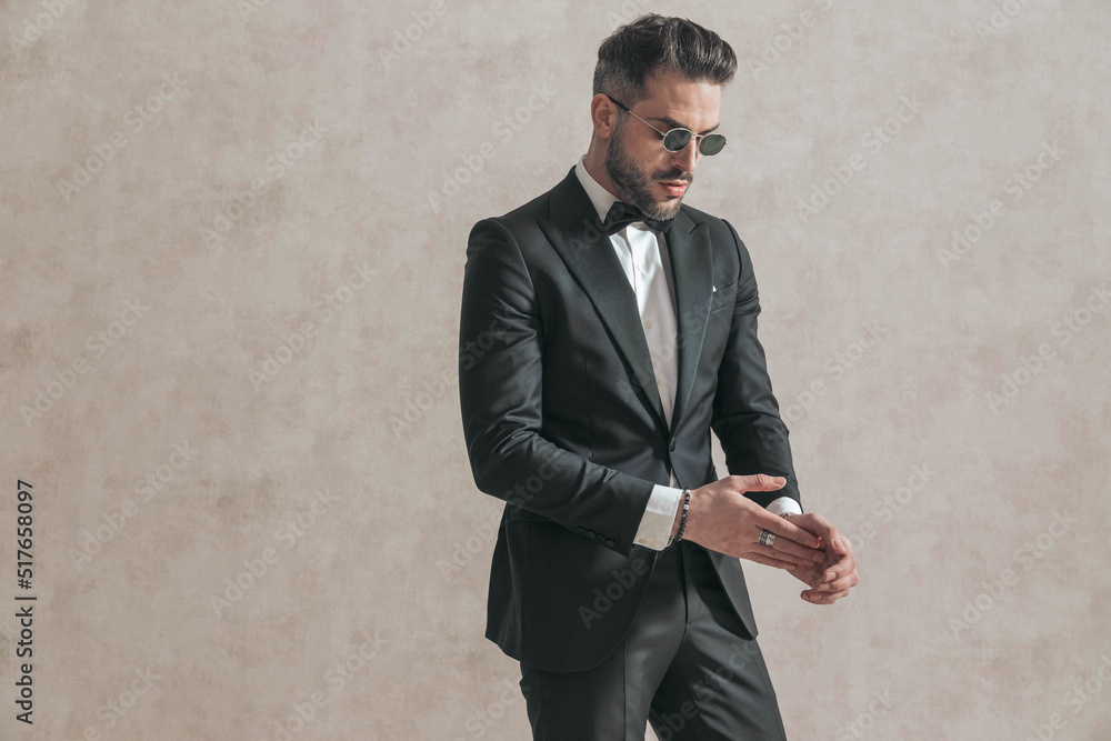 sexy elegant man wearing black tuxedo with bowtie rubbing palms sexy elegant man wearing black tuxedo with bowtie rubbing palms