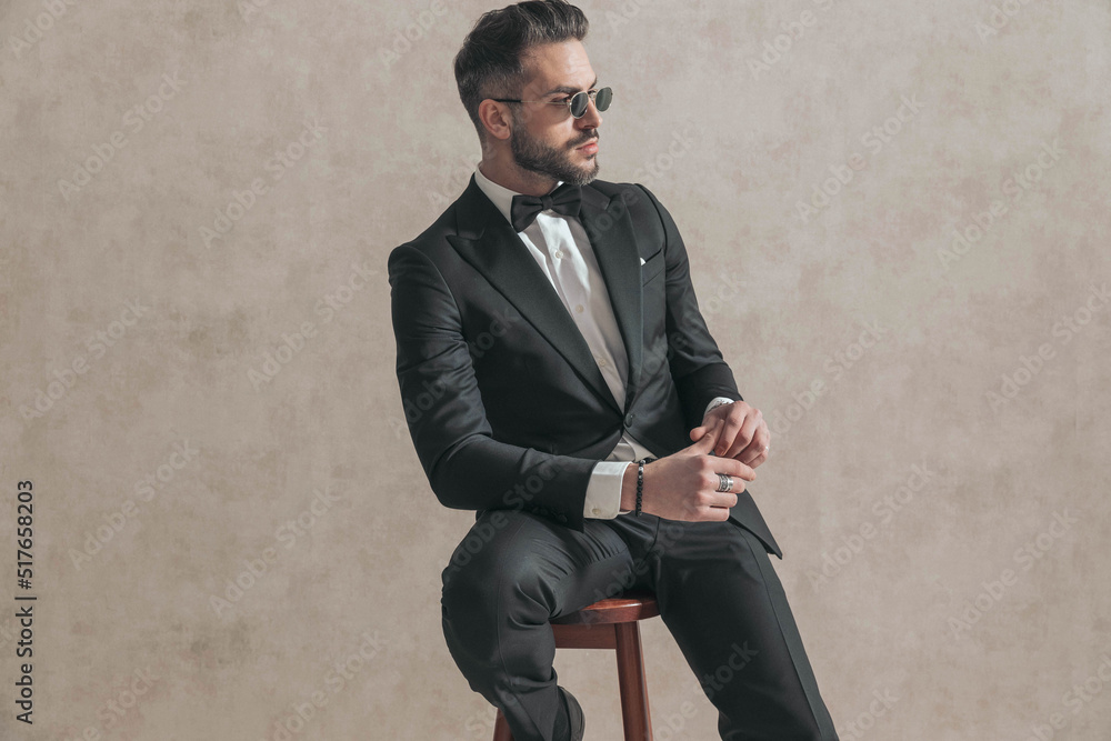 cool fashion stylish man in black tuxedo holding elbow on knee cool fashion stylish man in black tuxedo holding elbow on knee