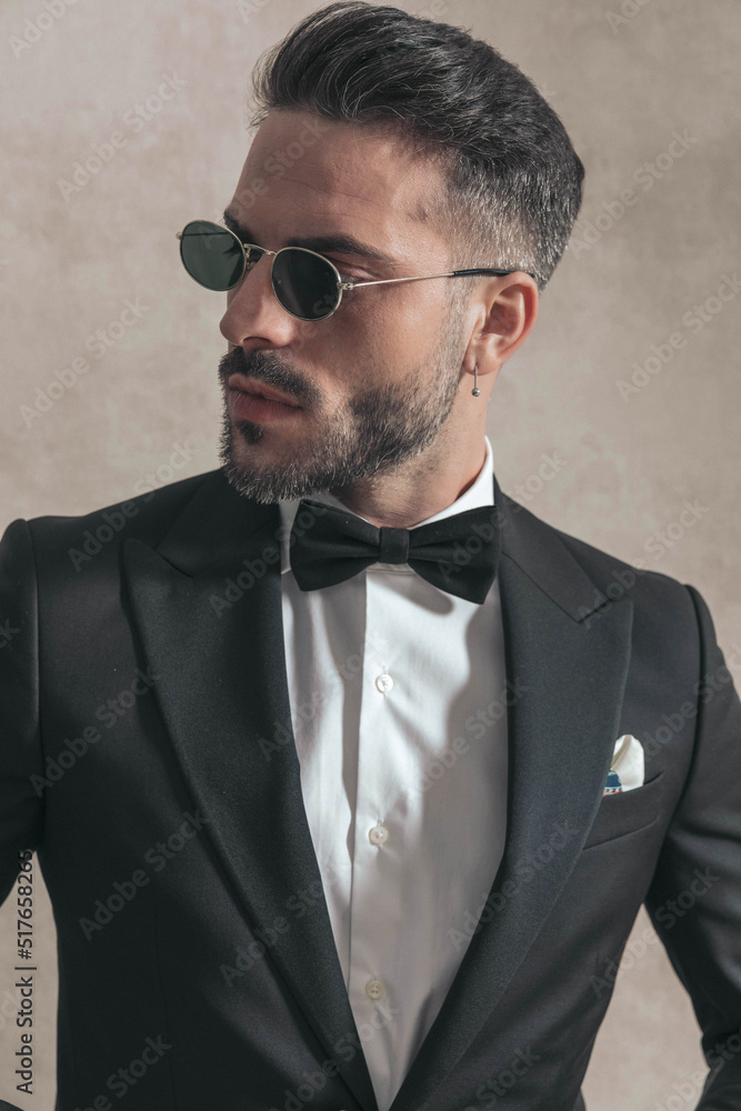 unshaved businessman with bowtie and sunglasses looking to side unshaved businessman with bowtie and sunglasses looking to side