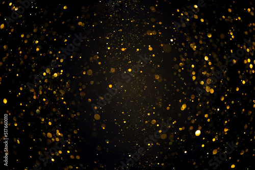 Swirly bokeh of gold glitter shimmer dust shiny particles dark abstract background