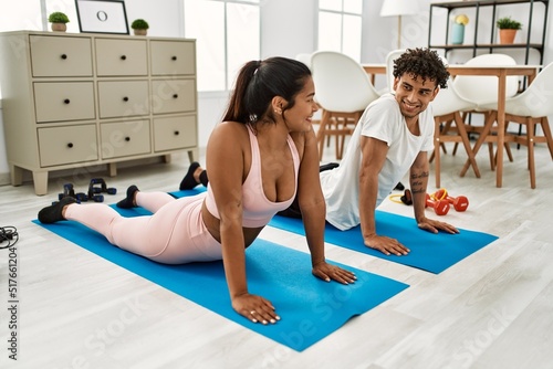 Young latin couple smiling happy training yoga pose at home.