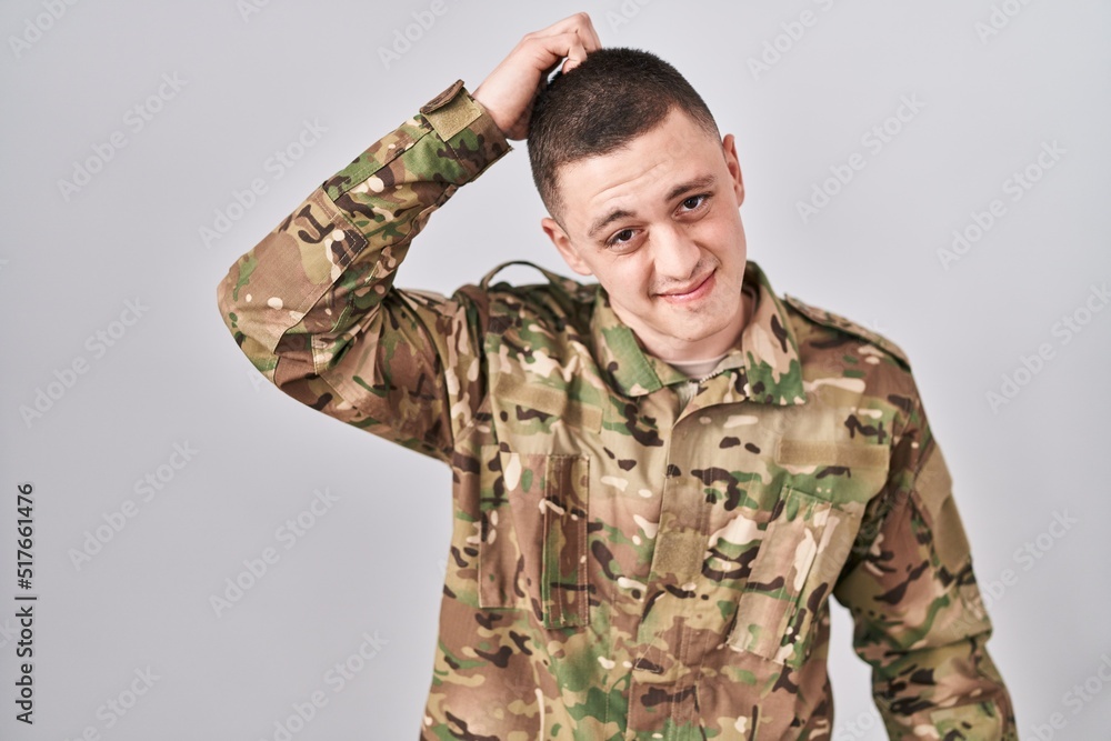 Young man wearing camouflage army uniform confuse and wonder about question. uncertain with doubt, thinking with hand on head. pensive concept.