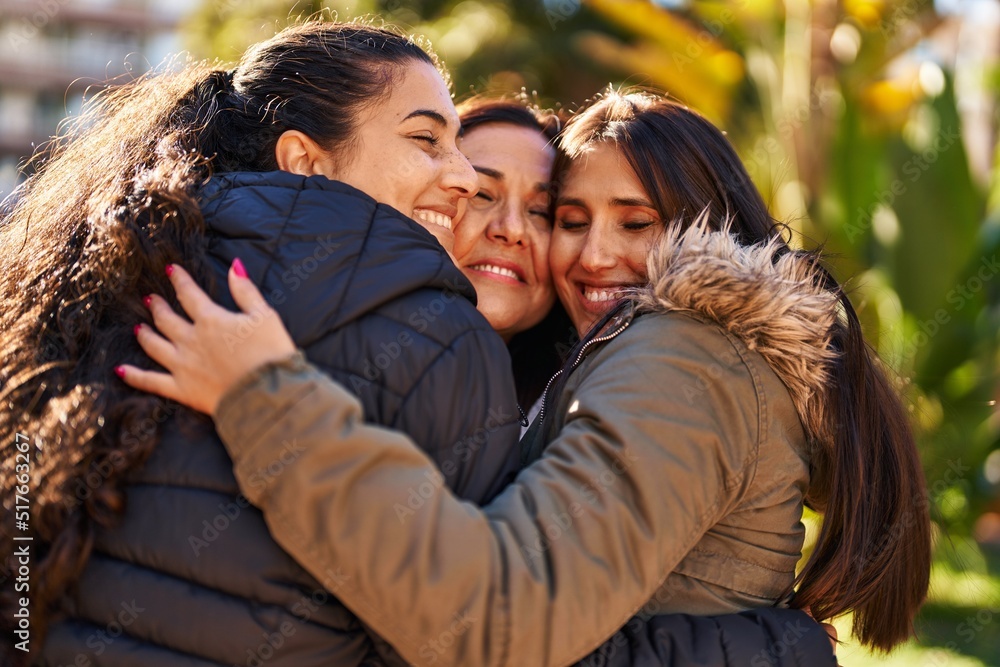 Fototapeta premium Three woman mother and daughters hugging each other at park