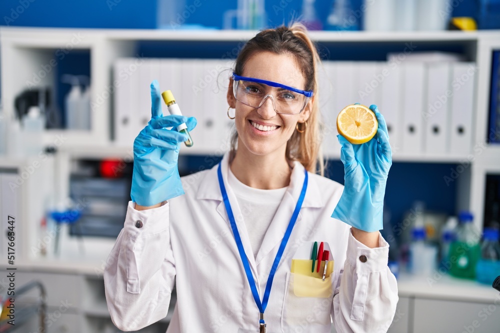 Young woman scientist holding test tube and lemon at laboratory Young woman scientist holding test tube and lemon at laboratory
