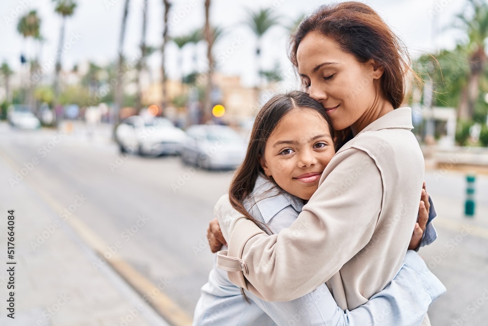 Woman and girl mother and daughter hugging each other at street Woman and girl mother and daughter hugging each other at street
