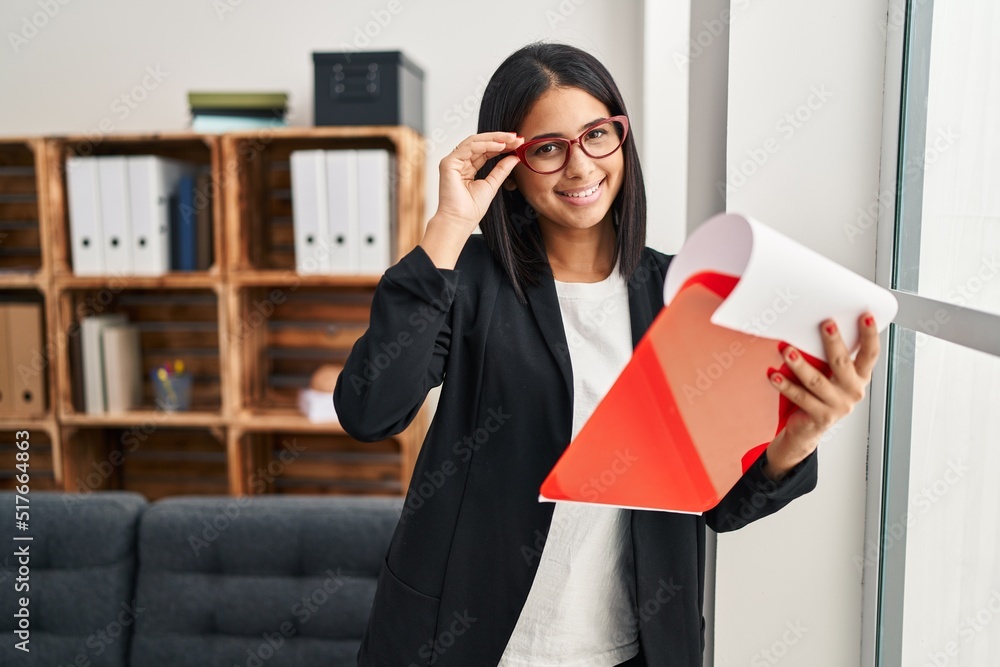 Young latin woman psychologist holding clipboard standing at clinic Young latin woman psychologist holding clipboard standing at clinic