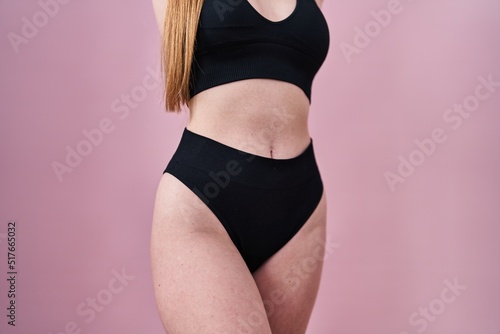 Young caucasian woman wearing lingerie standing over isolated pink background