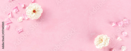 Floral panorama with a white roses and flower petals on a pink background, overhead flat lay panoramic banner, a wedding invitation design template