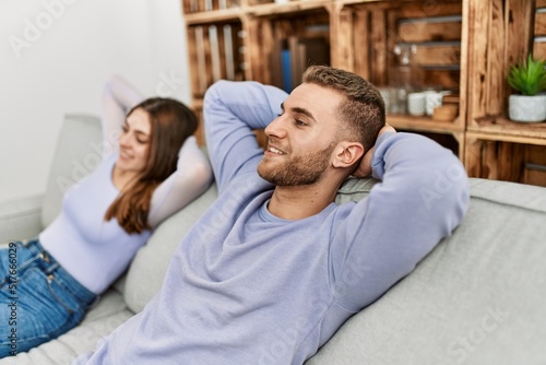 Young caucasian couple resting with hands on head sitting on the sofa at home.