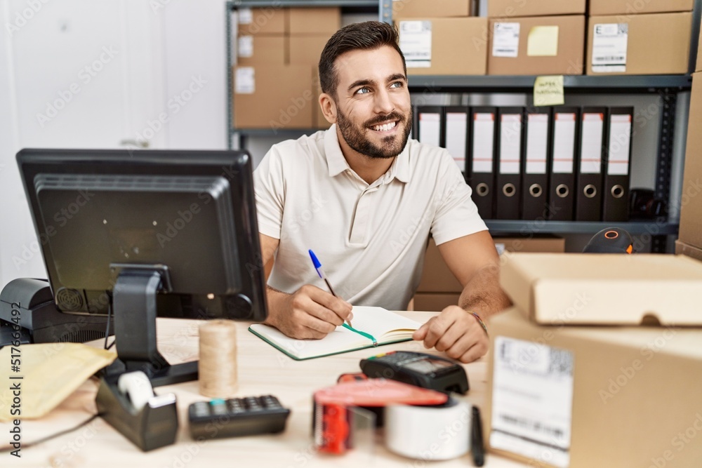 Young hispanic man smiling confident writing on notebook at storehouse Young hispanic man smiling confident writing on notebook at storehouse