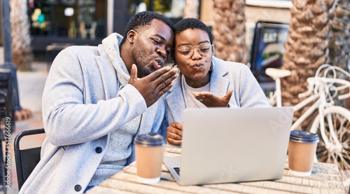 Man and woman couple having video call sitting on table at coffee shop terrace