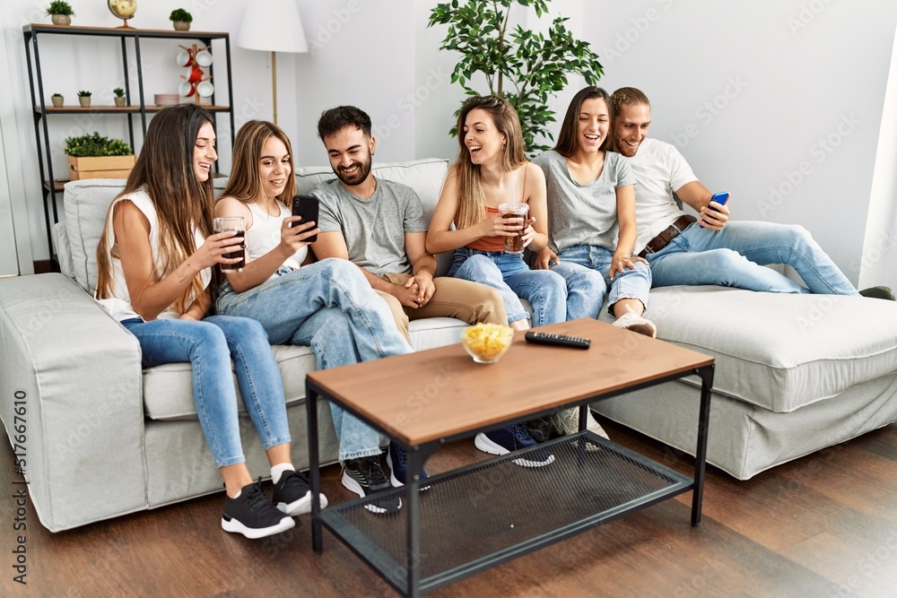 Group of young friends smiling happy and using smartphone sitting on the sofa at home. Group of young friends smiling happy and using smartphone sitting on the sofa at home.