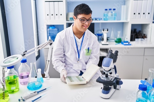 Down syndrome man wearing scientist uniform working at laboratory