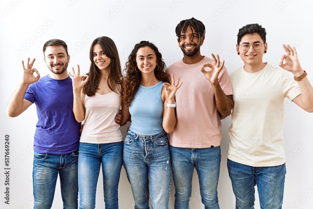 Group of young people standing together over isolated background smiling positive doing ok sign with hand and fingers. successful expression. Group of young people standing together over isolated background smiling positive doing ok sign with hand and fingers. successful expression.