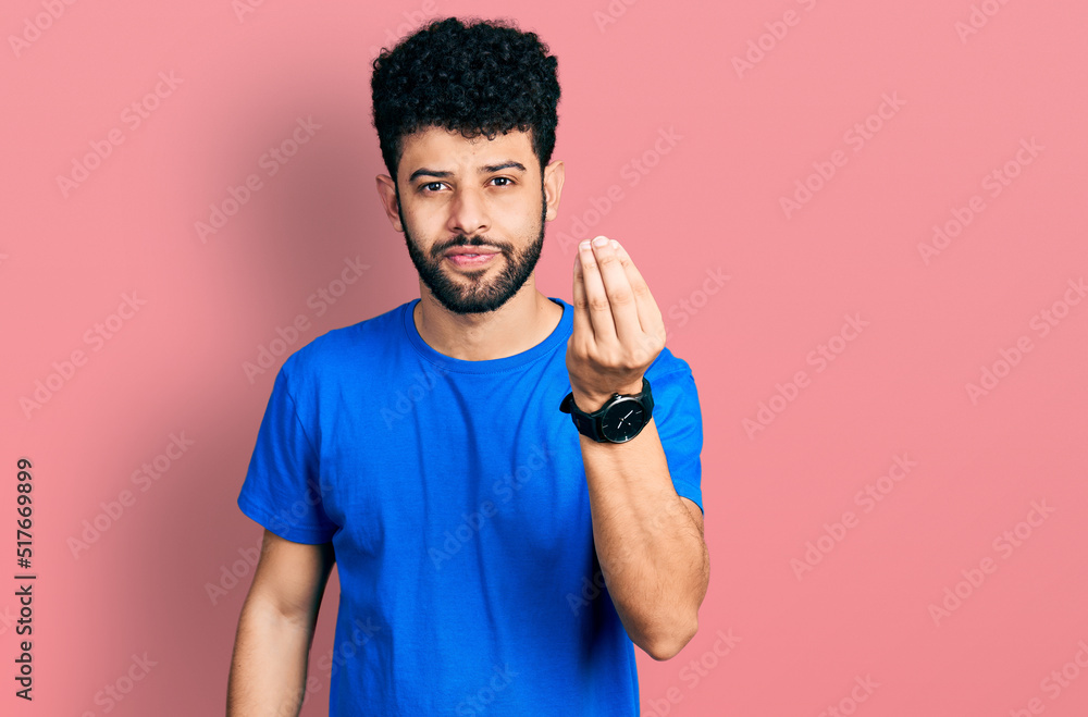 Young arab man with beard wearing casual blue t shirt doing italian gesture with hand and fingers confident expression Young arab man with beard wearing casual blue t shirt doing italian gesture with hand and fingers confident expression