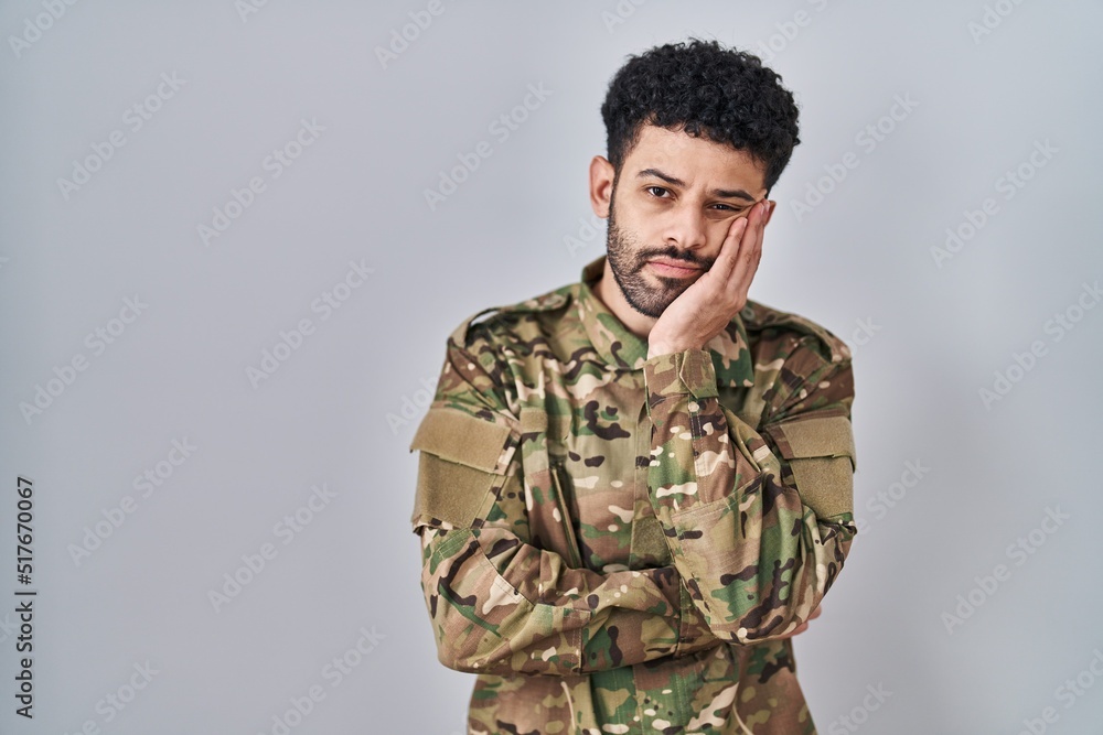 Arab man wearing camouflage army uniform thinking looking tired and bored with depression problems with crossed arms.