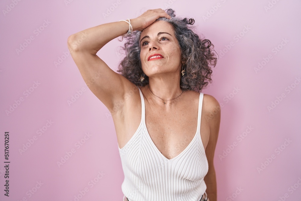 Middle age woman with grey hair standing over pink background smiling confident touching hair with hand up gesture, posing attractive and fashionable Middle age woman with grey hair standing over pink background smiling confident touching hair with hand up gesture, posing attractive and fashionable
