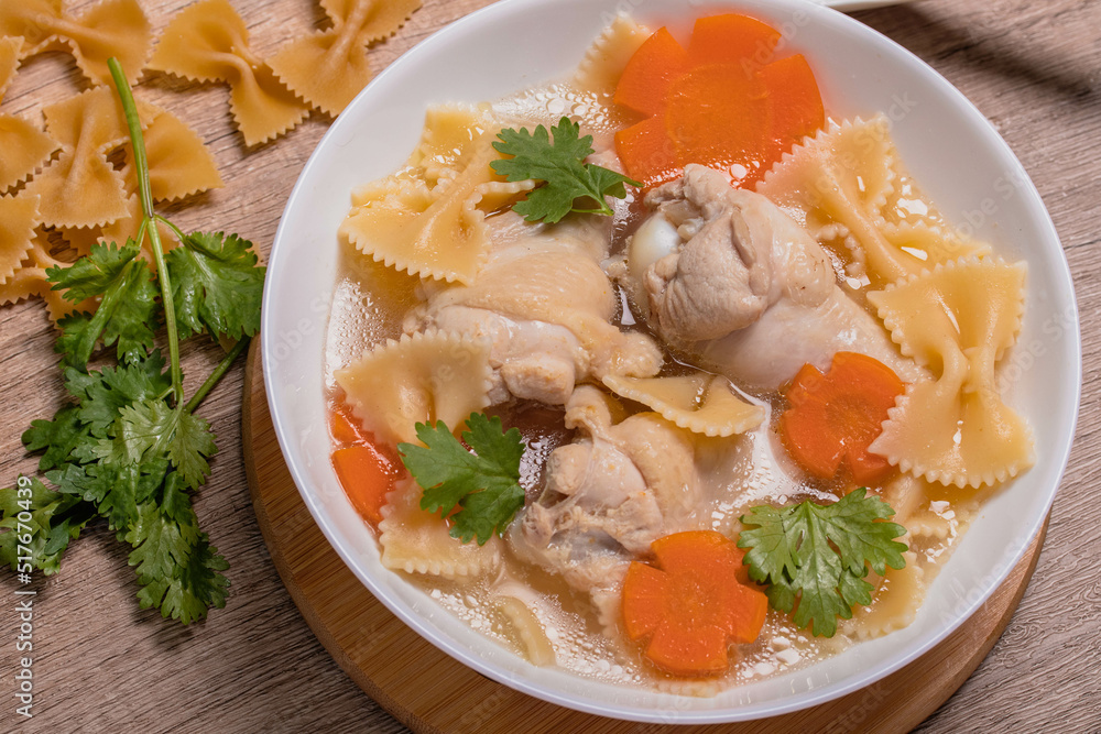 Macaroni soup with chicken thighs in clear broth with carrots.on an rustic old wood background. Macaroni soup with chicken thighs in clear broth with carrots.on an rustic old wood background.