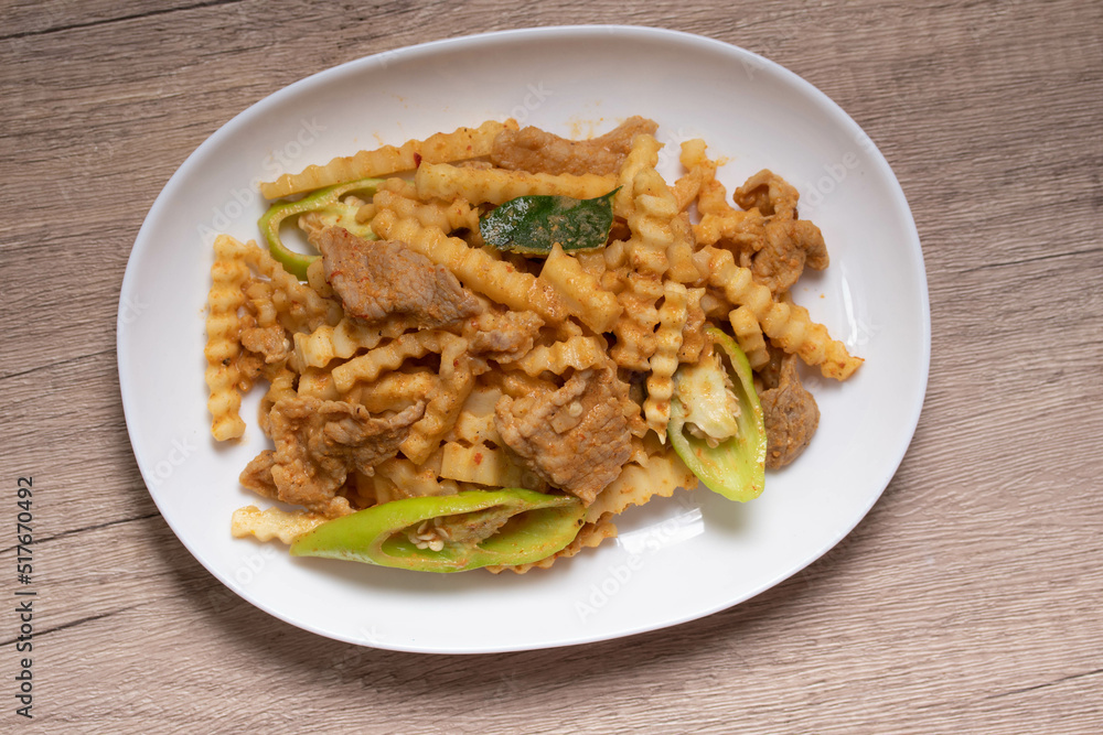 Stir-fried pork with red curry paste and young coconut shoots in a white plate Stir-fried pork with red curry paste and young coconut shoots in a white plate