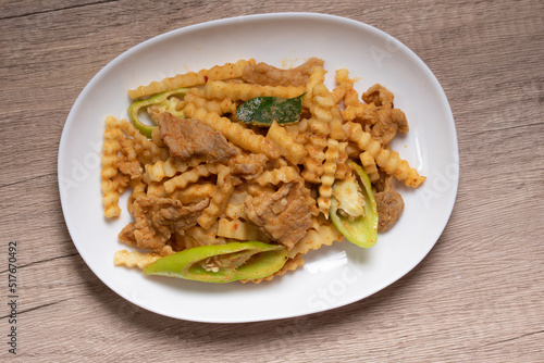 Stir-fried pork with red curry paste and young coconut shoots in a white plate