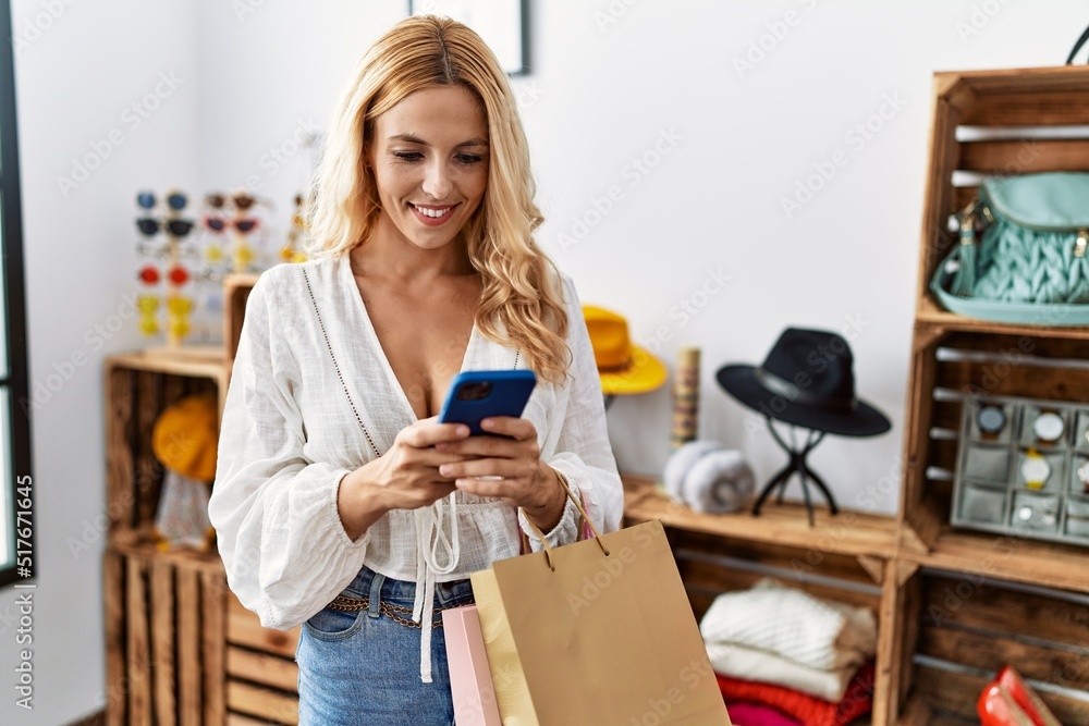 Young blonde woman using smartphone shopping at clothing store Young blonde woman using smartphone shopping at clothing store