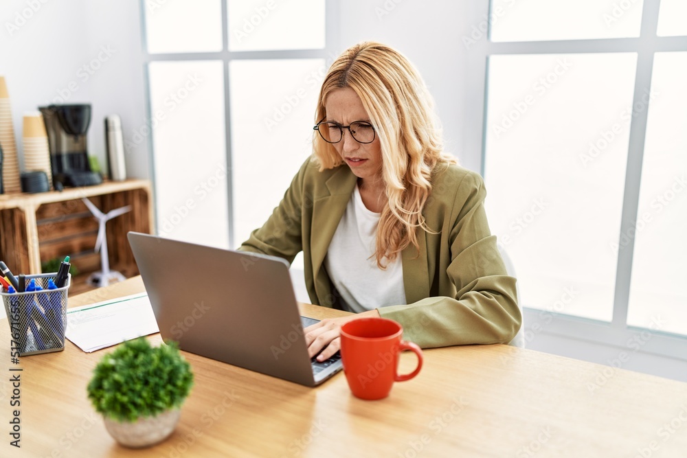 Beautiful blonde woman working at the office with laptop skeptic and nervous, frowning upset because of problem. negative person. Beautiful blonde woman working at the office with laptop skeptic and nervous, frowning upset because of problem. negative person.