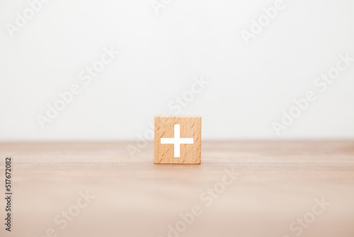 ＋の文字。プラス。加法。増加。木製ブロックに書かれている。白い文字。木製テーブルの背景。 photo