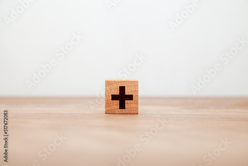 ＋の文字。プラス。加法。増加。木製ブロックに書かれている。黒い文字。木製テーブルの背景。 photo