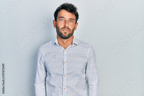 Handsome man with beard wearing casual elegant shirt with serious expression on face. simple and natural looking at the camera.