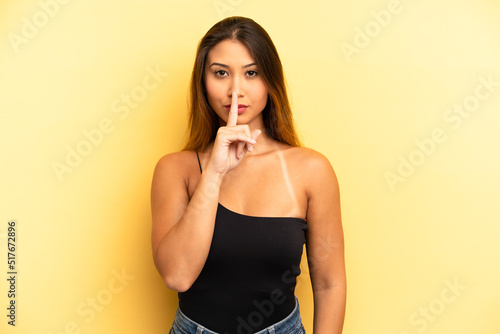 asian pretty woman looking serious and cross with finger pressed to lips demanding silence or quiet, keeping a secret