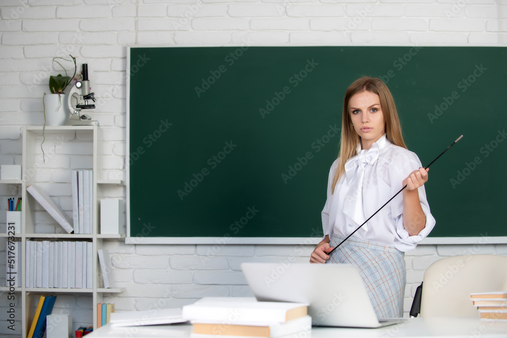 Young teacher with pointer. Portrait of a young, confident and attractive female student studying in school classroom. Young teacher with pointer. Portrait of a young, confident and attractive female student studying in school classroom.