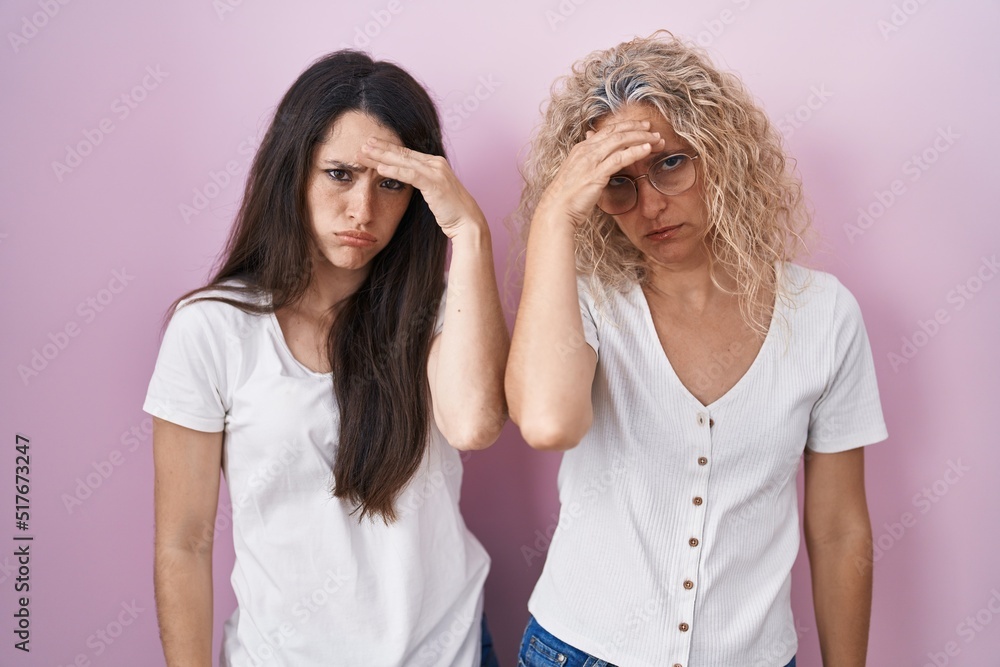 Mother and daughter standing together over pink background worried and stressed about a problem with hand on forehead, nervous and anxious for crisis Mother and daughter standing together over pink background worried and stressed about a problem with hand on forehead, nervous and anxious for crisis