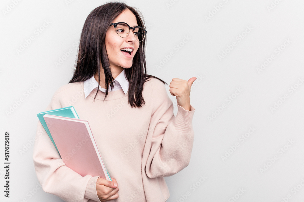 Young student caucasian woman isolated on white background points with thumb finger away, laughing and carefree. Young student caucasian woman isolated on white background points with thumb finger away, laughing and carefree.