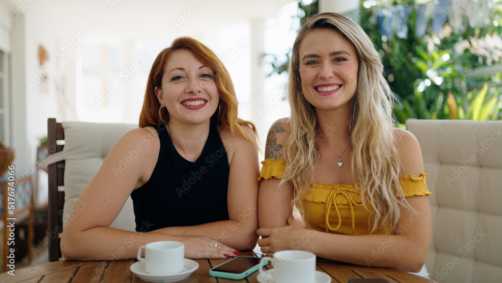 Two women drinking coffee sitting on table at home terrace Two women drinking coffee sitting on table at home terrace
