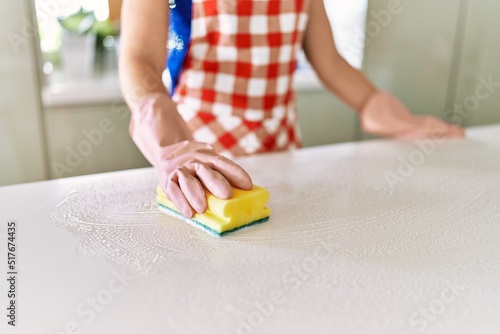 Young woman cleaning table at kitchen