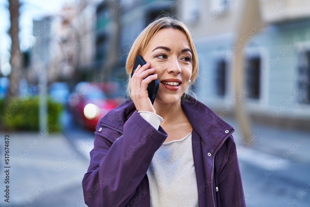 Young woman smiling confident talking on the smartphone at street