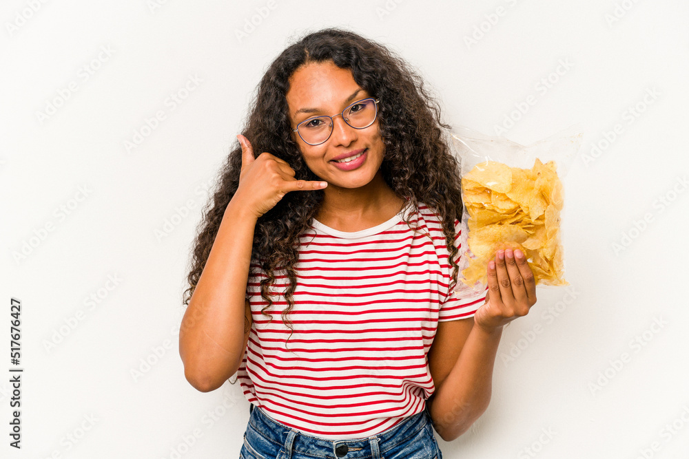 Young hispanic woman holding crips isolated on white background showing a mobile phone call gesture with fingers. Young hispanic woman holding crips isolated on white background showing a mobile phone call gesture with fingers.
