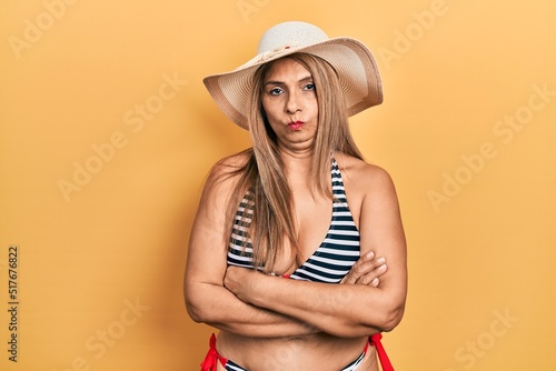 Middle age hispanic woman wearing bikini and summer hat skeptic and nervous  disapproving expression on face with crossed arms. negative person.