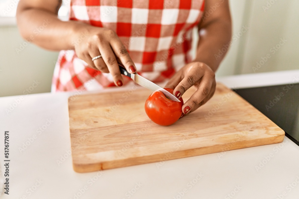 Hispanic brunette woman cooking cutting tomatoes at the kitchen Hispanic brunette woman cooking cutting tomatoes at the kitchen