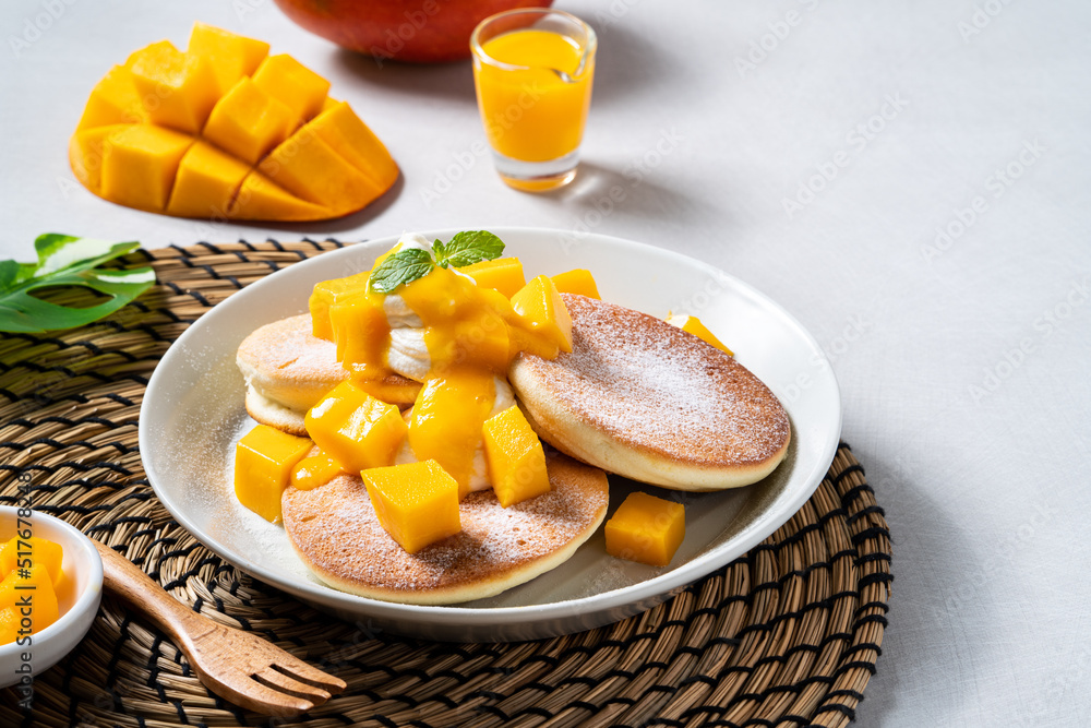 Delicious Japanese souffle pancake with dice mango and jam on white table background. Delicious Japanese souffle pancake with dice mango and jam on white table background.