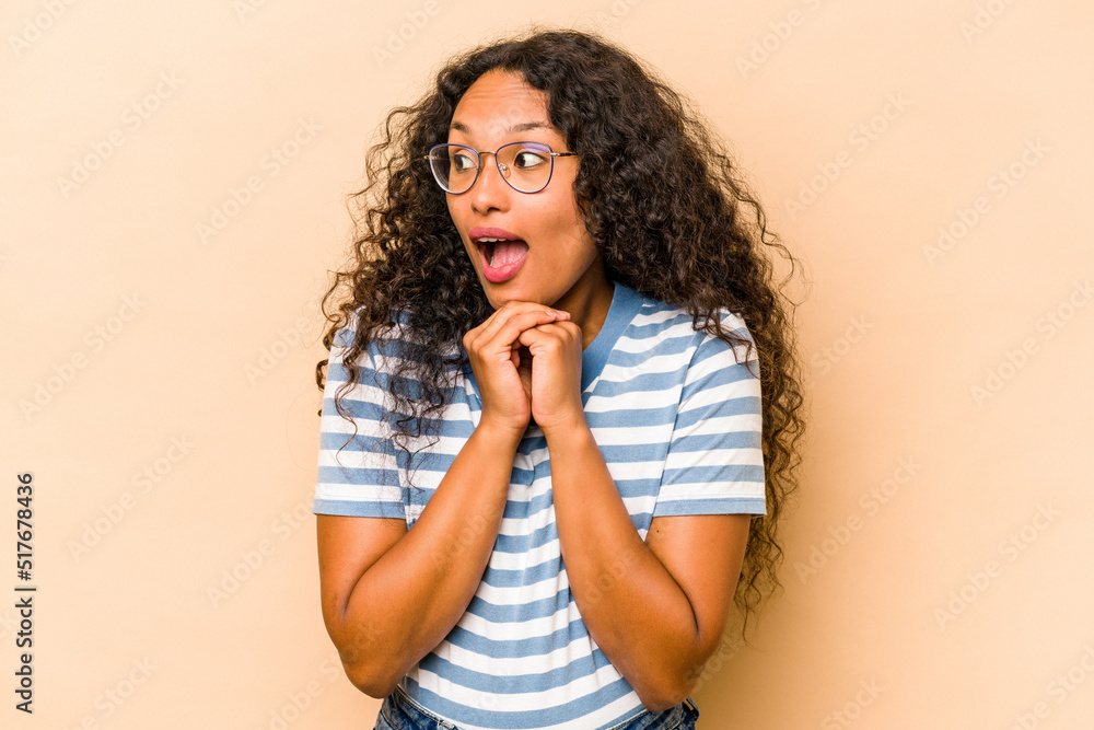 Young hispanic woman isolated on beige background praying for luck, amazed and opening mouth looking to front. Young hispanic woman isolated on beige background praying for luck, amazed and opening mouth looking to front.